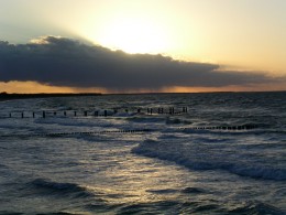 Sonnenuntergang am Meer mit dunkler Regenwolke