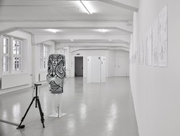 Puppe mit Kleid und Videoprojektion in Galerie