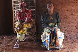 zwei afrikanische Frauen aus dem Kongo sitzen nebeneinander in einer Lehmhütte