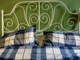 Weißes Bett mit blauen Bettbezug und olivgrüne Wand