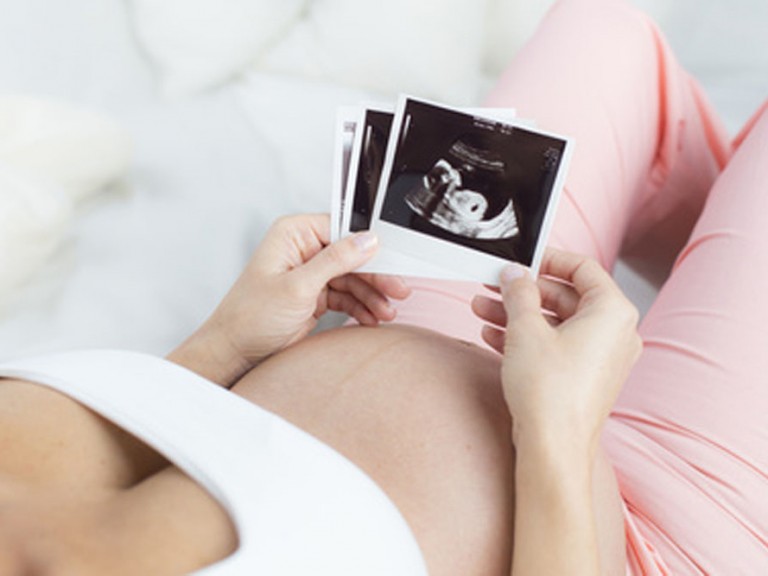 Schwangere Frau betrachtet Ultraschallbild