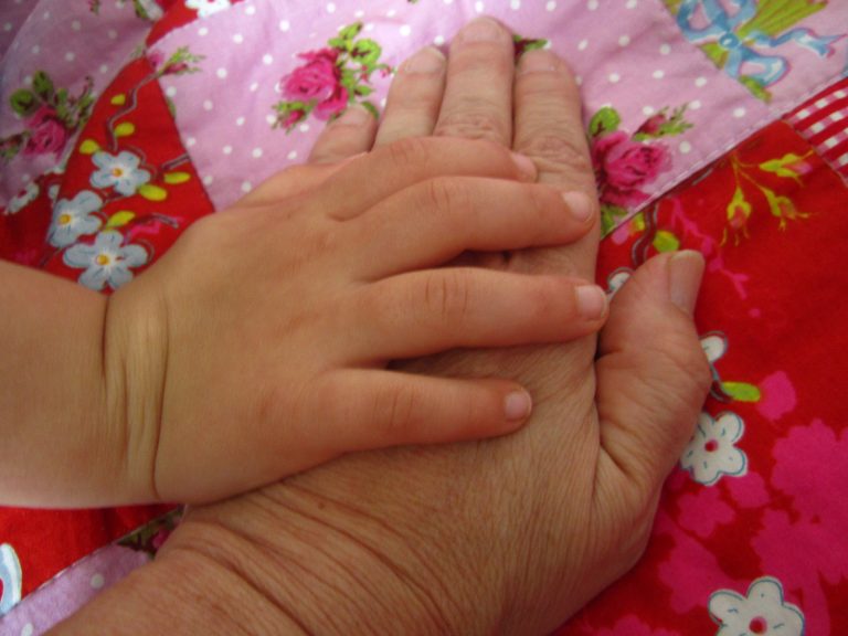 Kinderhand streichelt alte Hand