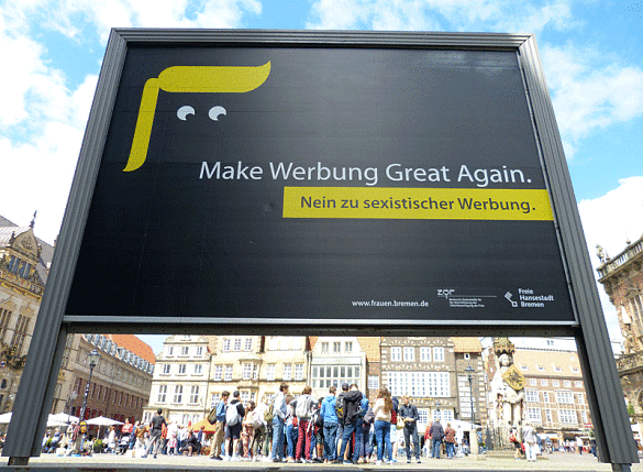 Schwarzes Werbeplakat mit Trum-Rolle und Kulleraugen vor Marktplatzpanorama, auf dem geschrieben steht: Make Werbung Great Again. Nein zu sexistischer Werbung.