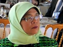 malay Frau mit Kopftuch und Brille sitzend