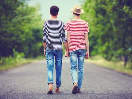 Junges homosexuelles Paar geht Hand in Hand auf einer Straße