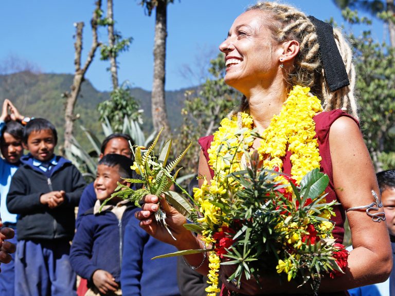 Stella Deetjen mit Blumenkette umgeben von nepalesischen Kindern