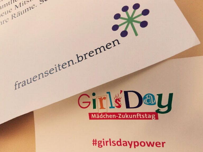 Auf einem Zettel sieht man das Girls'Day Logo, darunter steht Mädchenzukunftstag und #girlsdaypower. Auf einem anderen Zettel ist das Logo der frauenseiten.bremen zu sehen