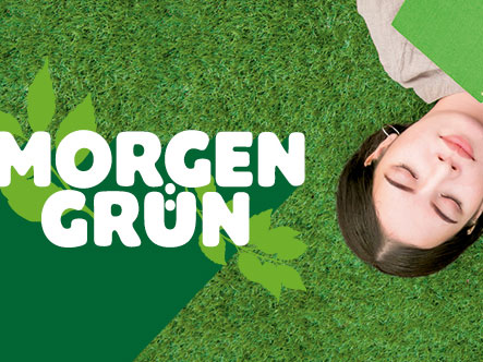Ein Mädchen mit braunen Haaren liegt rücklings auf einer grünen Wiese und hält einen grünen Block in ihren Händen. Ihre Augen sind geschlossenen. Neben ihr sieht man das Logo des Schreibwettbwerb Morgengrün.