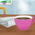 Ein rosafarbener Becher mit Kaffee steht auf einem Tisch. Daneben liegt eine Zeitung. Im Hintergrund sieht man zwei lila Stuhllehnen und einen Ausschnitt eines Fensters