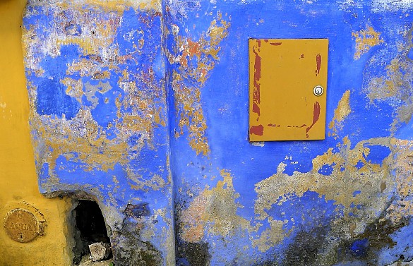 Die Fotografie "Wandwerk" der Künstlerin Regina Contzen, die Teil der Werkschau Blick.Art in der ZGF ist. Es zeigt eine leicht heruntergekommene Wand, die zum größten Teil blau ist. An einigen Stellen ist die Farbe jedoch abgeblättert. Andere Stellen sind gelb.