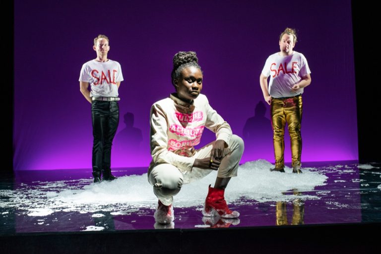 Drei Personen auf einer Bühne mit Badeschaum und violettem Hintergrund, v.l. Patrick Güldenberg, Lorna Ishema, Sascha Nathan