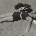Schwarz-weiß Fotografie einer Frau, die auf dem Rücken im Sand liegt