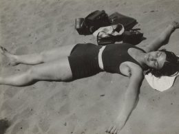 Schwarz-weiß Fotografie einer Frau, die auf dem Rücken im Sand liegt
