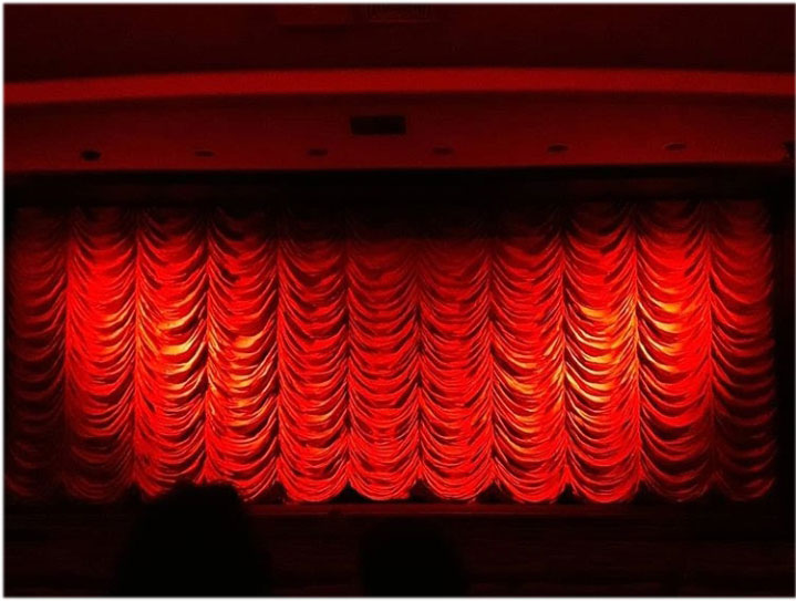 Es ist ein roter Vorhang in einem Kinosaal von vorne zu sehen