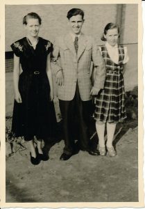 Altes Foto in Schwarz-Weiß von einer Frau, einem Mann und einer Jugendlichen, die nebeneinander stehen und in die Kamera schauen.