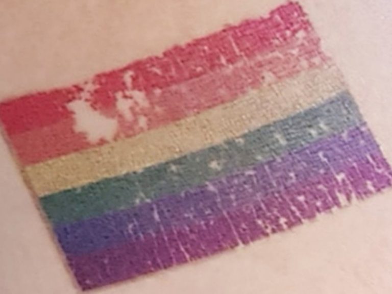 Ein abblätterndes Bild einer Regenbogenflagge auf Haut