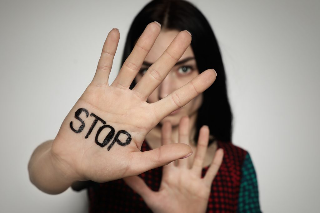 Junge Frau mit Hand in im Vordergrund auf der Stop geschrieben steht