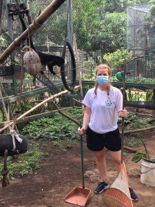 Frau mit Mundschutz reinigt Tierkäfig in Costa Rica