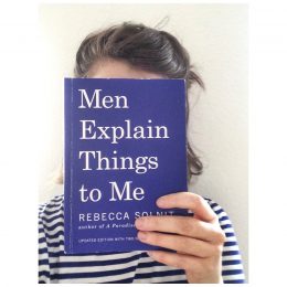 Zu sehen ist das Buch „Men explain things to me“, das von Theresa Schlesinger vor das Gesicht gehalten wird