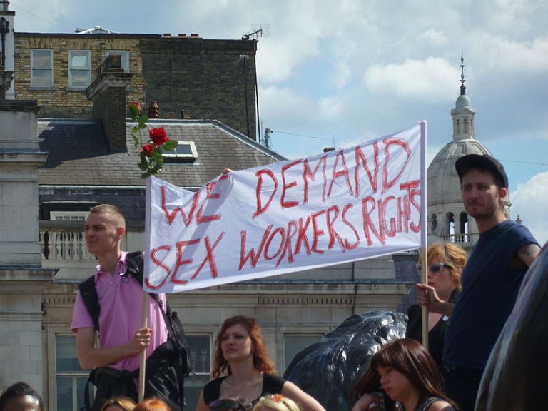 Protest von Sexarbeiter*innen, Zwei Männer heben die Fahne