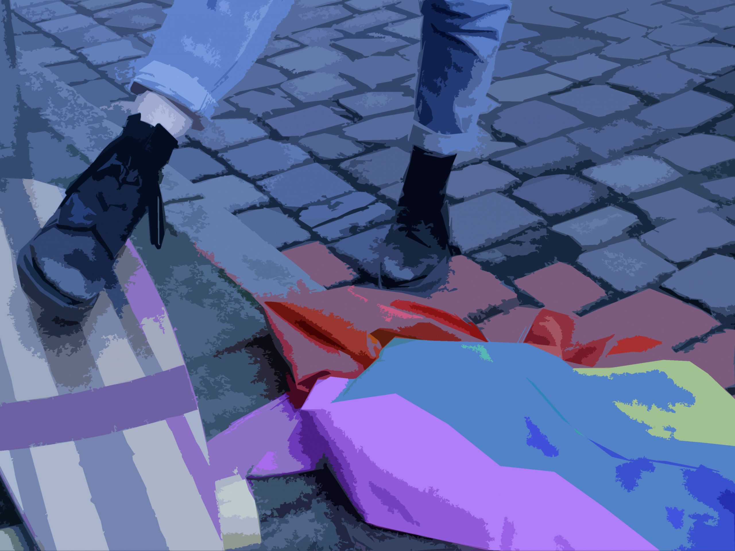 Auf der Straße. Ein Longboard liegt neben einer Gay Pride Flagge auf dem Bordstein. Eine Person (zu sehen sind nur die Beine von den Knien abwärts) steht mit einem Fuß lässig auf dem Board.