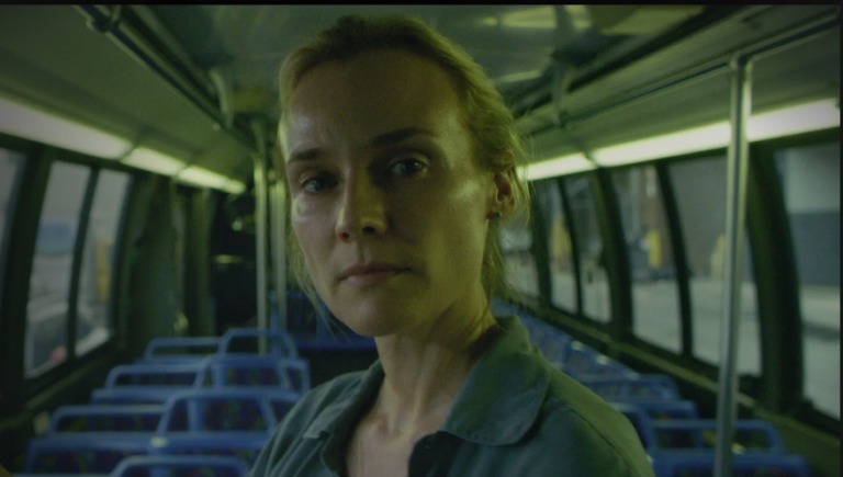 Eine Frau steht im Gang eines leeren Buses. Mam sieht ihr Gesicht.