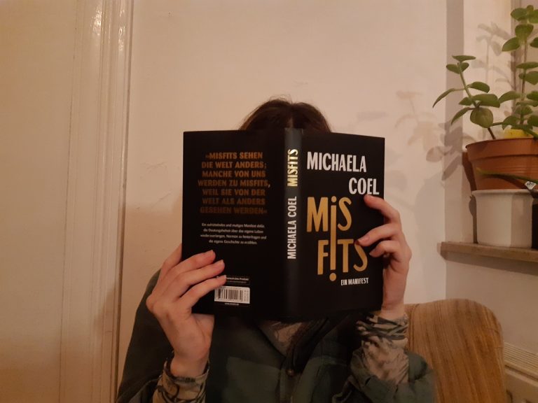 Foto einer Person, die das Buch Misfits von Michaela Coel liest