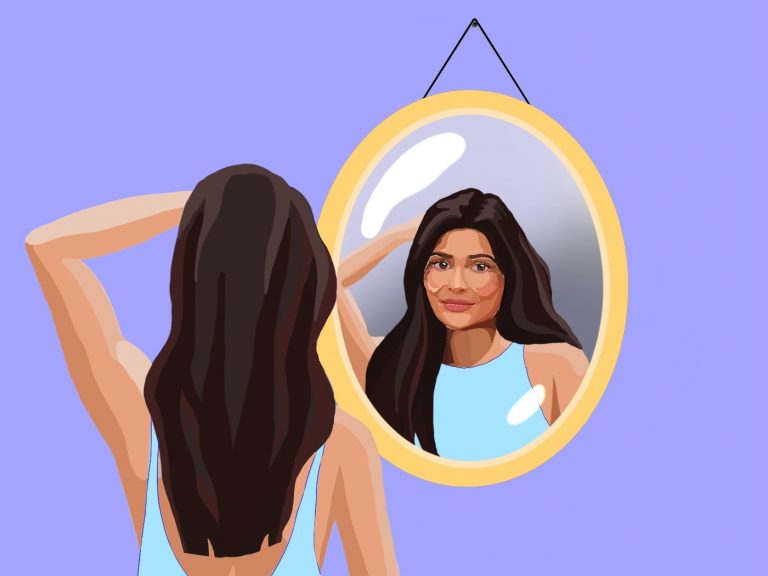 Eine hübsche junge Frau mit braunem Haar und hellblauen Top betrachtet sich im Spiegel