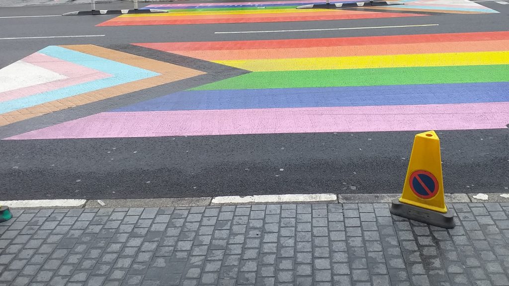 Foto einer Regenbogenflagge auf die Straße gesprayt