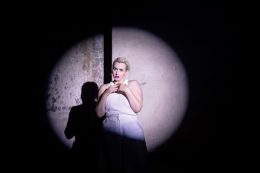 Frau im Scheinwerferlicht auf einer Bühne in weißer Kleidung