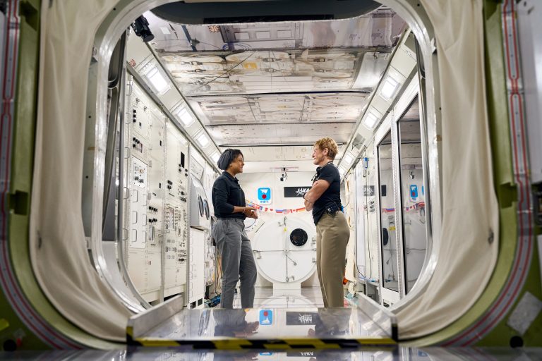 Astronautinnen Rayyanah Barnawi und Peggy Whiston stehen sich in einem Raumfahrzeug gegenüber