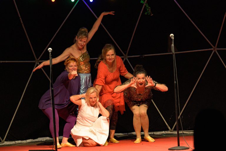 Zu sehen sind die fünf Schauspielerinnen des Theaterstücks Cats On Fire auf einer Bühne. Jede der Frauen macht eine unterschiedliche Pose.