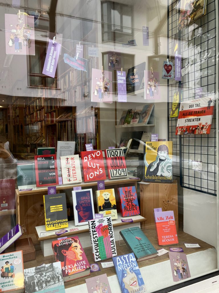 Zu sehen ist, das von uns dekorierte Buchfenster bei der Albatros Buchhandlung. Wir haben feministische Bücher, Sticker, Patches und Postkarten ästhetisch präsentiert.