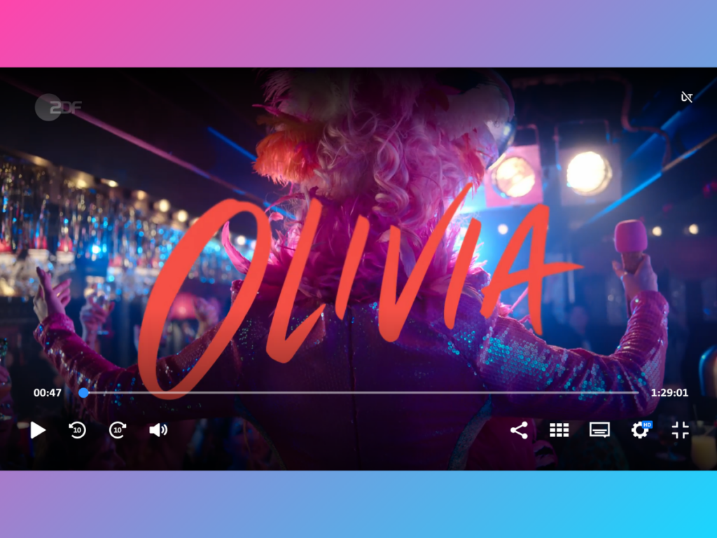 Titelbild vom Film "Olivia", zeigt Olivia von hinten in einem Club, mit einer pinken Perrücke und einem Mikrofon in der Hand. Darüber steht groß der Titel "Olivia".