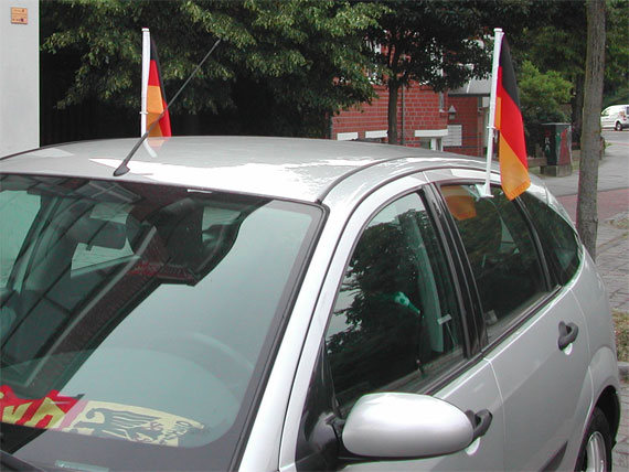 An einem Auto sind Deutschlandfahnen an den Türen befestigt