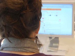 Digitale Gewalt, Frau sitzt am PC, zu sehen ist ihr Hinterkopf vor dem Bildschirm